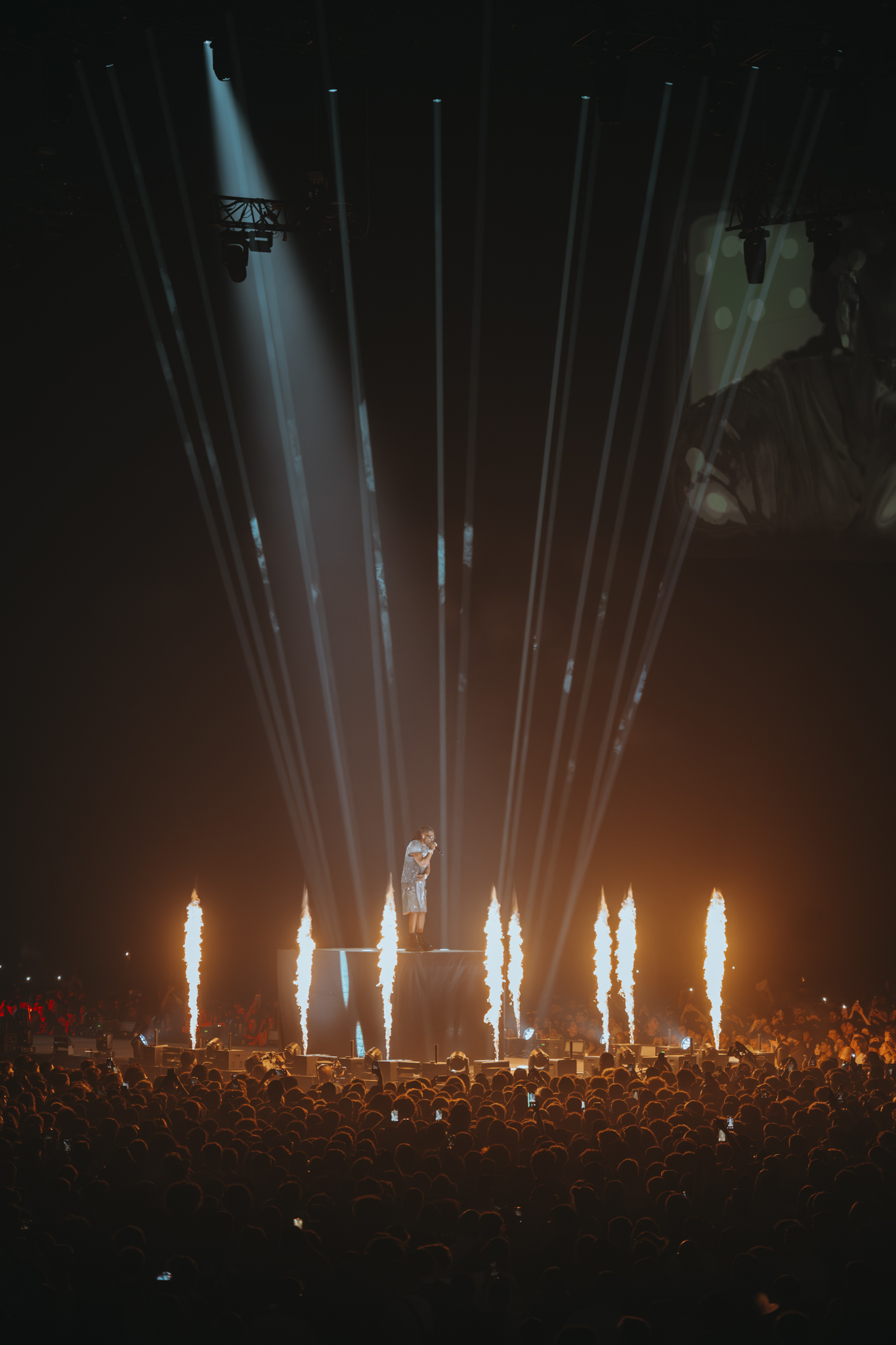 Photo verticale de Gazo chantant avec de la pyrotechnie sur scène lors de son concert