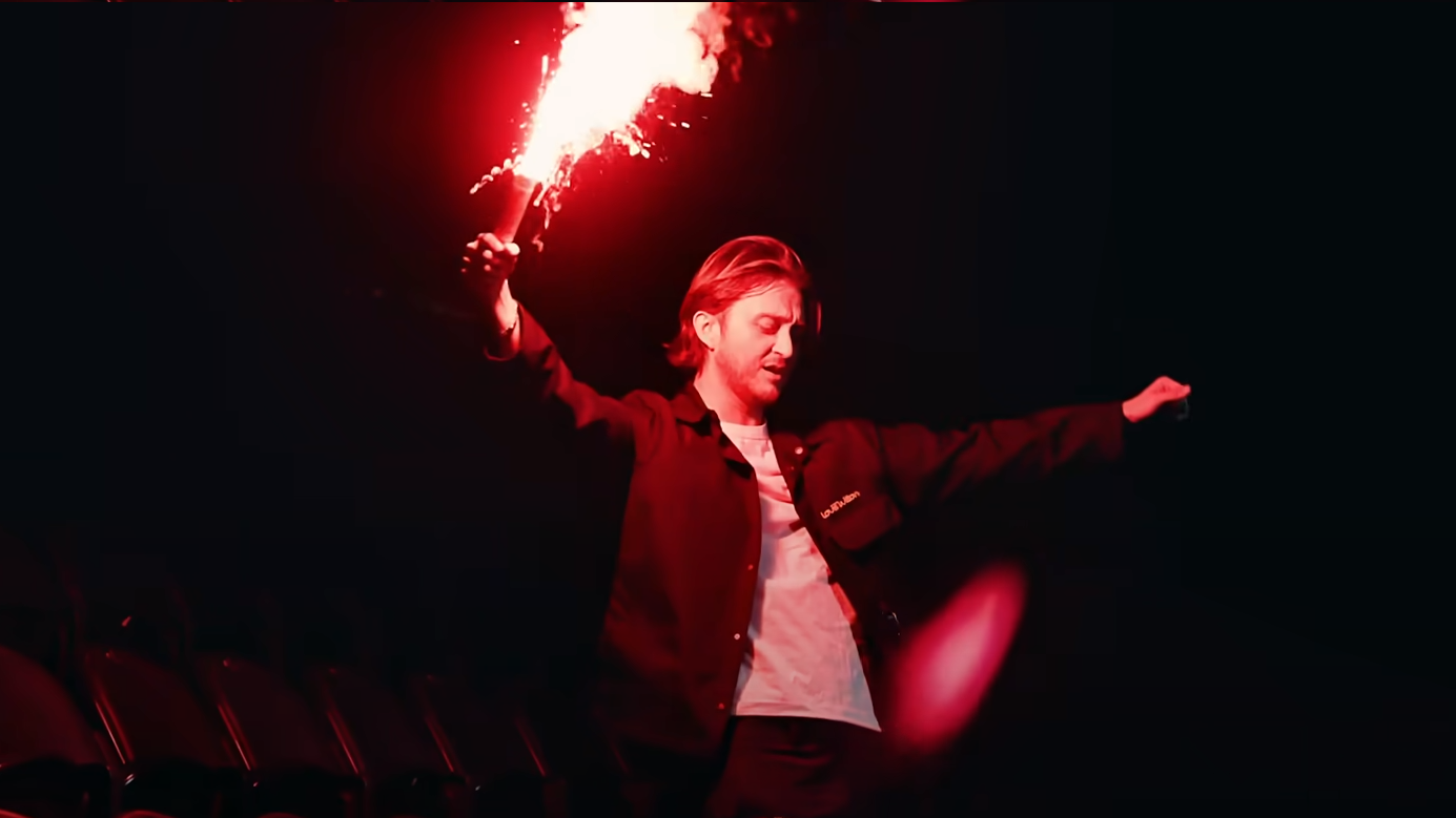 Photo de Vald lors du tournage de son clip à Paris La Défense Arena avec un fumigène dans la main